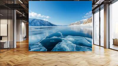 In winter, the frozen surface of lake is covered with blue ice and surrounded by snow-capped mountains under clear skies. The photograph uses a wide-angle lens to capture the vast, snowy landscapes. Wall mural