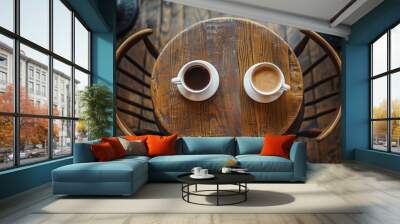 Top view of two coffee cups on a round wooden table, chairs visible in the background. The setting is a cozy cafe interior, adding to its charm with dark wood grain patterns. Wall mural