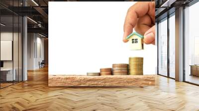 Human hand putting house model on coins stack, saving or investment for a house on white background. Wall mural