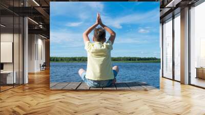 boy doing yoga in nature by the lake Wall mural