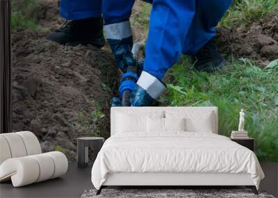 hands of the worker, in blue gloves, laid a plastic pipeline in an open trench in the ground Wall mural