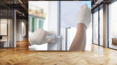 worker in white gloves, checks the tightness of the plastic window, using a white sheet of paper Wall mural