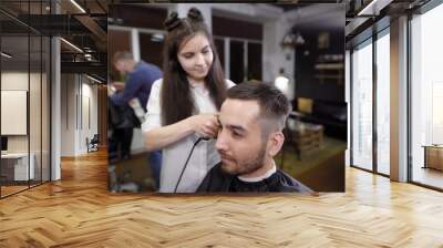 Woman barber trimming hair at her customer with hair clipper. Barber shop scene Wall mural