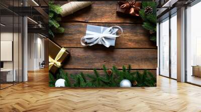 Preparing for Christmas or New Year holiday. Flat-lay of fur tree branches, evergreen wreaths, christmas wraped gift, wooden table background, top view, copy space Wall mural