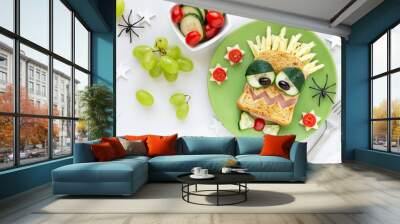 Fun food for kids - cute smiling monster face sandwich with ham and cheese, served with fresh tomatoes and cucumbers Wall mural