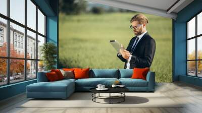 Man with tablet at field Wall mural