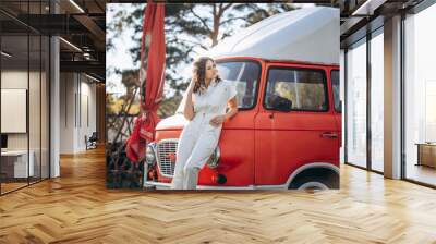 Beautiful young brunette woman in a white jumpsuit, at the red trailer bus Wall mural