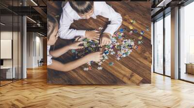 Happy boy and girl collect puzzle lying on the floor Wall mural