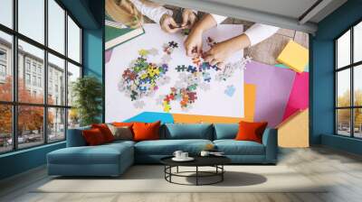 Two preschool age child put the puzzle together on the floor, hands close up Wall mural