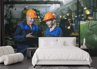 two workers at an industrial plant with a tablet in hand, working together manufacturing activities Wall mural