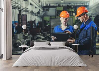 two workers at an industrial plant with a tablet in hand, working together manufacturing activities Wall mural