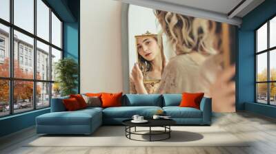 Young beautiful model girl with natural makeup looks at her reflection in the mirror Wall mural