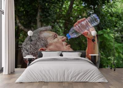 Mature man drinking water from a bottle on a hot day Wall mural