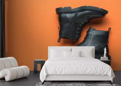 A pair of neatly stacked black shoes on an orange background. Place for text. Wall mural