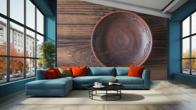 Clay bowl on a brown wooden table. The view from the top. Pottery for the kitchen. Wall mural