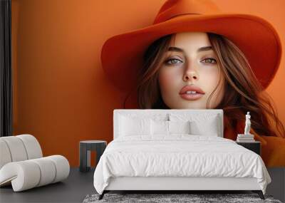 Fashionable Woman in Orange Hat and Coat Posing Against Orange Background Wall mural