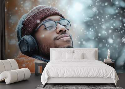 Young Man Enjoying Snowfall with Headphones and Winter Attire in Forest Setting Wall mural