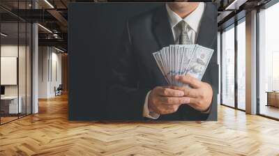 business man wearing suit and necktie holding money in hand on black background, US dollar (USD) bills Wall mural