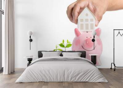 Growing Money - Hand man holding house model on piggy bank isolated Wall mural