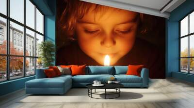 a birthday wish being made, a child's face illuminated by candlelight, eyes closed in hopeful anticipation Wall mural