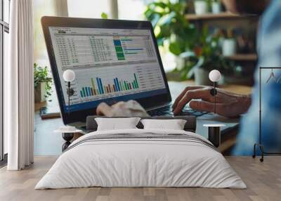 A businessman preparing a financial forecast on a laptop, working with detailed spreadsheets for economic planning and precise calculations. Wall mural