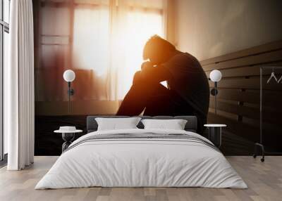 desperate man in silhouette sitting on the bed with hands on head Wall mural