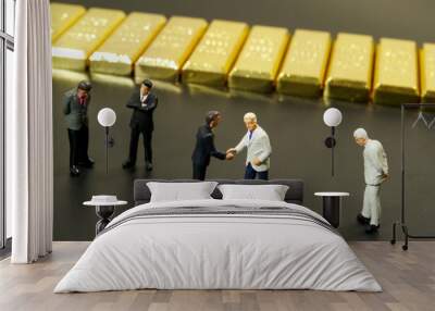 miniature people shaking hand with stack of gold bar on black background Wall mural