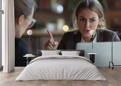 Two businesswomen in a close-up shot exchanging ideas over a laptop one pointing at the screen with intense focus on their expressions Wall mural