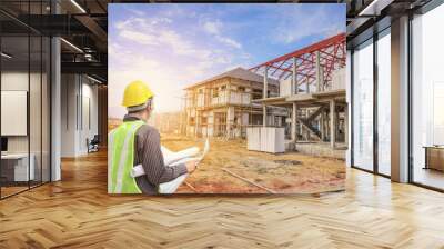 Professional engineer architect worker with protective helmet and blueprints paper at house building construction site Wall mural