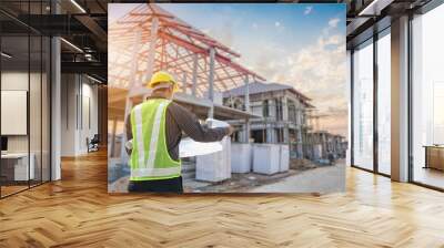 Professional engineer architect worker with protective helmet and blueprints paper at house building construction site Wall mural