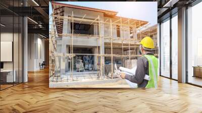 Professional engineer architect worker with protective helmet and blueprints paper at house building construction site Wall mural