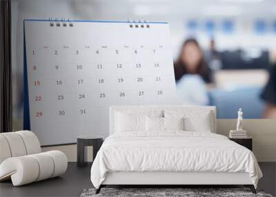 White paper desk calendar on wood table top with blurred office interior background Wall mural