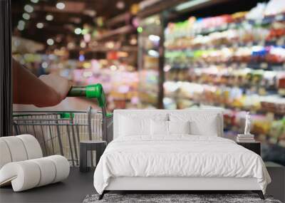 woman hand hold supermarket shopping cart with Abstract grocery store blurred defocused background with bokeh light Wall mural