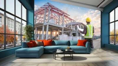 young professional engineer in protective helmet and blueprints paper at the house building construction site Wall mural