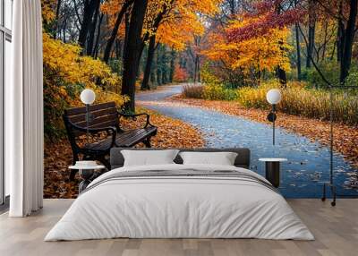 a wooden bench sitting on top of a leaf covered road Wall mural