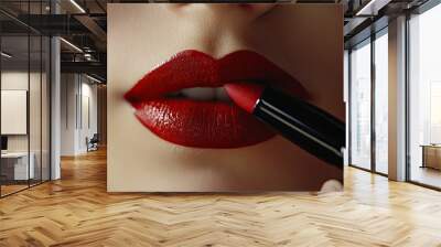 Detailed close-up of a woman's lips as she applies a bold red lipstick, emphasizing the art of perfecting a makeup look. Wall mural