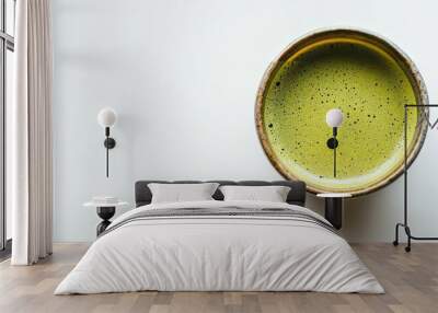 Top-down view of a vibrant matcha green tea cup on a white surface, highlighting the rich color and frothy texture of the beverage. Perfect for promoting health, wellness, or tea culture Wall mural