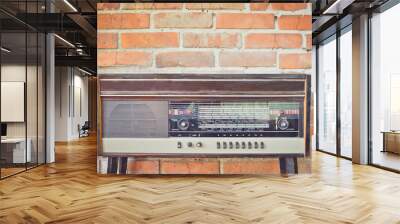 Old vintage antique radio on red brick wall background. Toned image. Copy space. Wall mural