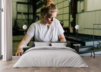 Woman welder working in construction and manufacturing cleans steel metal with a cloth with dirty hands Wall mural