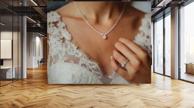 A close-up of the neckline of a wedding dress, with a girl's hand on it and a wedding ring on her ring finger Wall mural