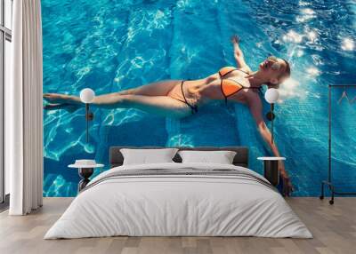 Beautiful woman relaxing in swimming pool of resort or hotel Wall mural