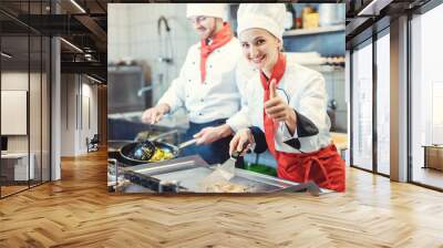 Chefs in restaurant kitchen cooking and giving the thumbs up as a sign of recommendation Wall mural