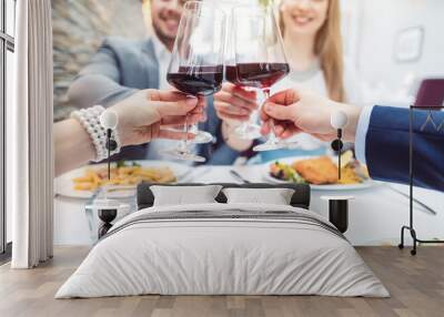 Close-up on hands of patrons in restaurant with glasses of red wine over table with food Wall mural