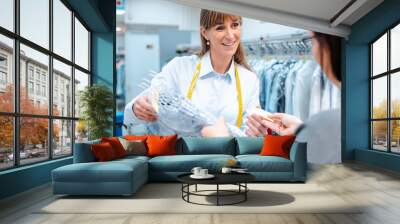 Customer in dry-cleaner shop getting back her clothes Wall mural