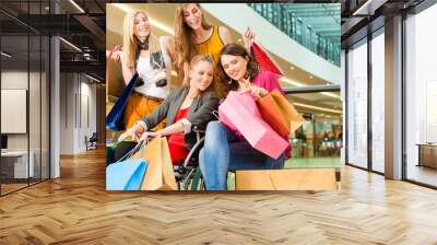 Four female friends shopping in a mall with wheelchair Wall mural