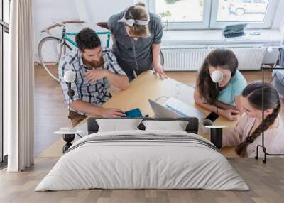 High-angle view of four young proficient digital nomads sharing ideas while using new technology in a contemporary collaborative office space Wall mural