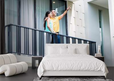 Indian woman and man standing on balcony of house Wall mural