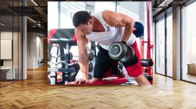 man with dumbbells at sport in fitness gym Wall mural