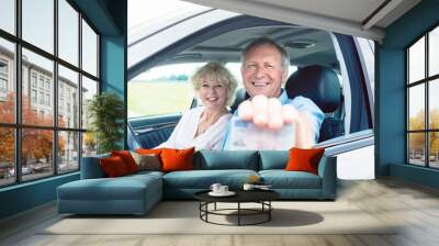 portrait of a happy senior man showing his available driving license while sitting in the car next t Wall mural