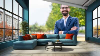 Portrait of confident businessman with crossed arms standing in the park Wall mural